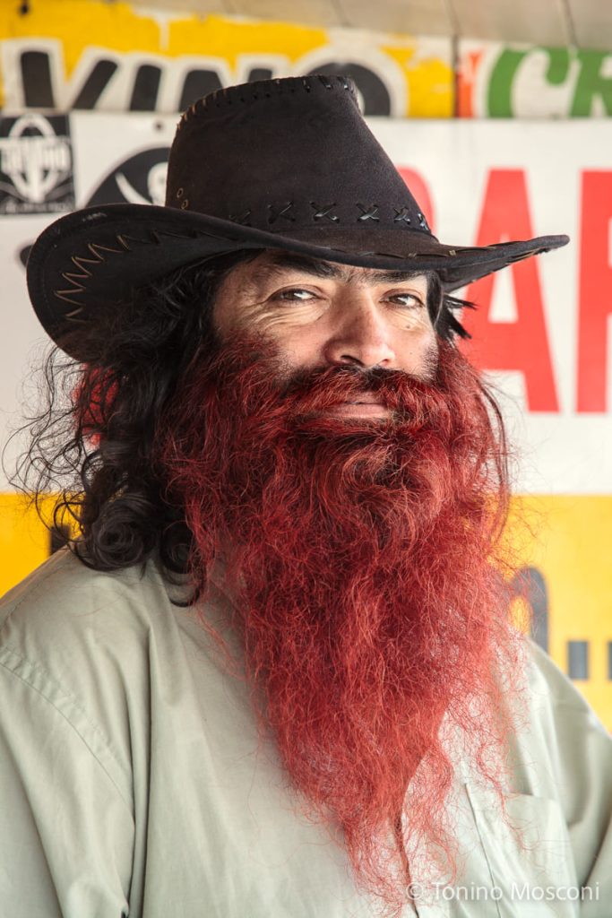 Ritratto di Tonino Mosconi di un ragazzo con barba e capelli rossi, che indossa un cappello e fissa dritto in camera.