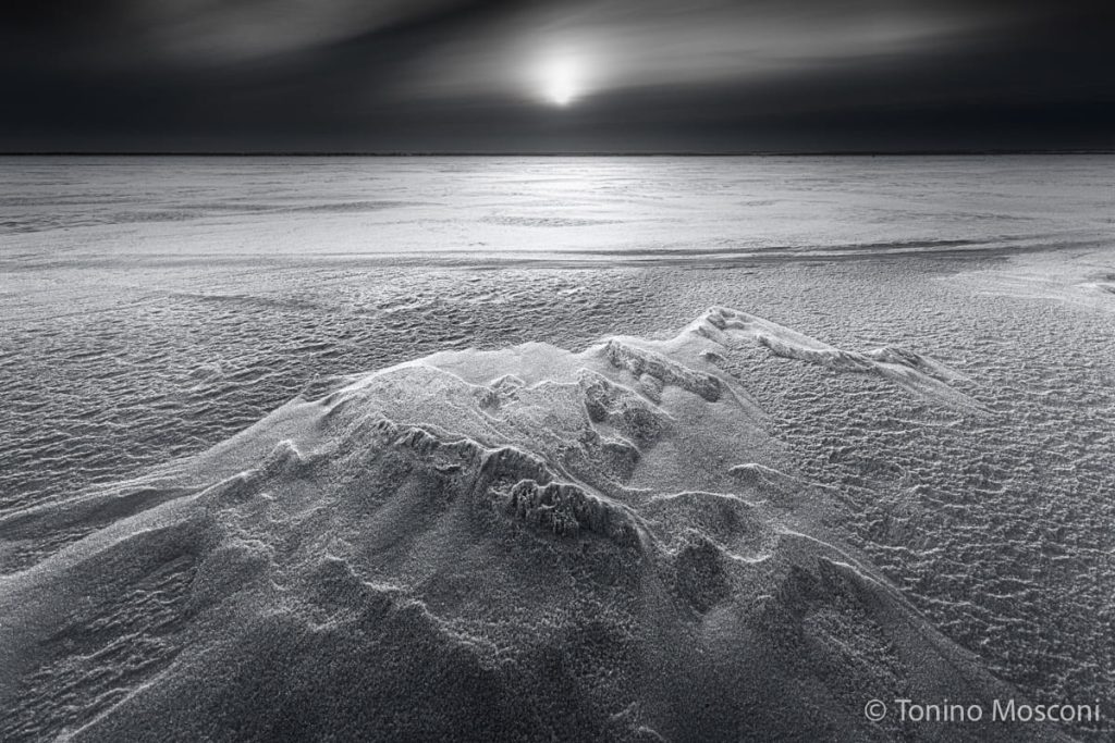 Fotografia di Tonino Mosconi ritraente una distesa di neve al chiarore della luce.